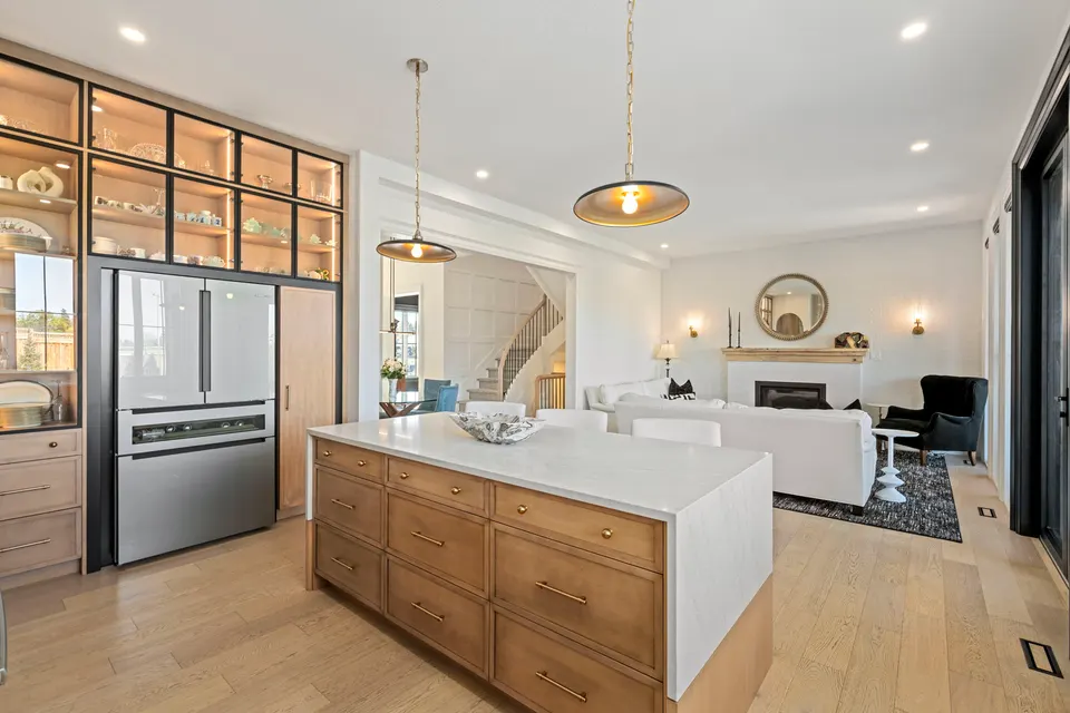Kitchen island, lit display cabinetry and the great room beyond