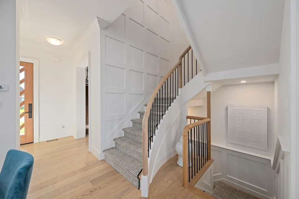Curved staircase with black spindles, a carpet runner and panelled walls