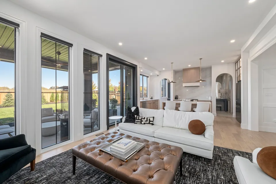 Great room with the wall of black-framed doors to the covered porch, the kitchen beyond