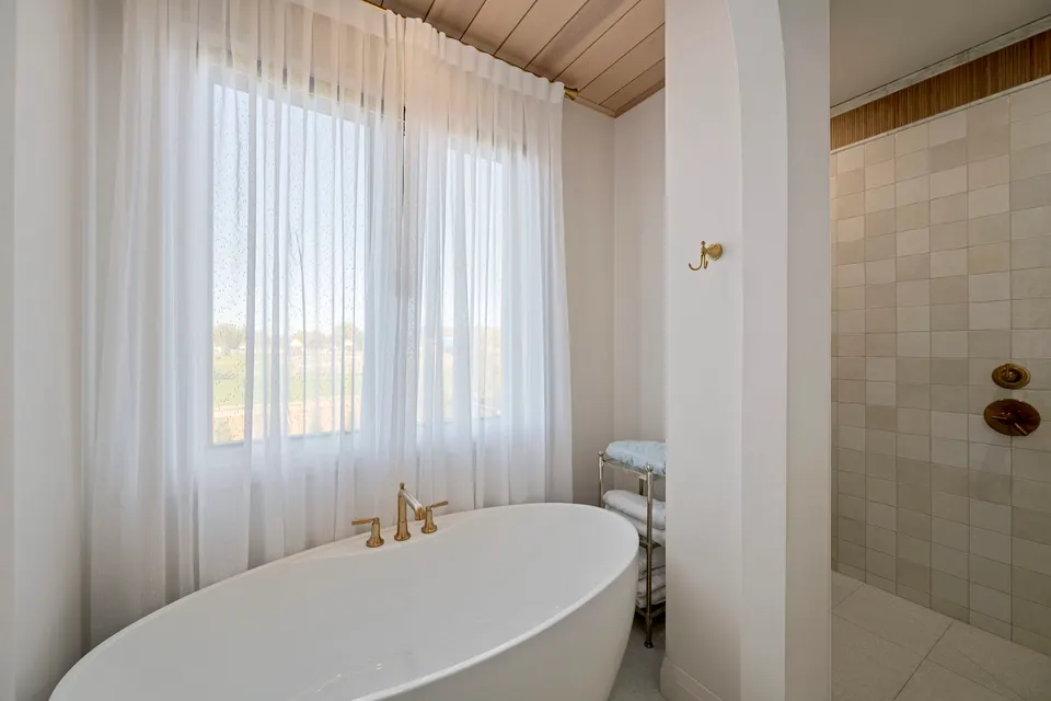 Freestanding tub under a wood ceiling in the primary ensuite