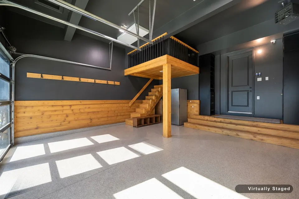 Inside the finished garage: Wrought Iron walls, cedar wainscoting, the cedar stair to the loft and the door into the house, virtually staged